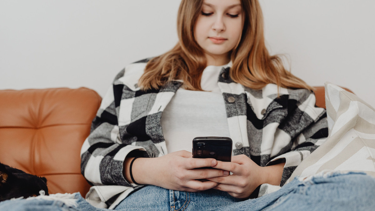 Young woman sitting on a couch looking down at her phone