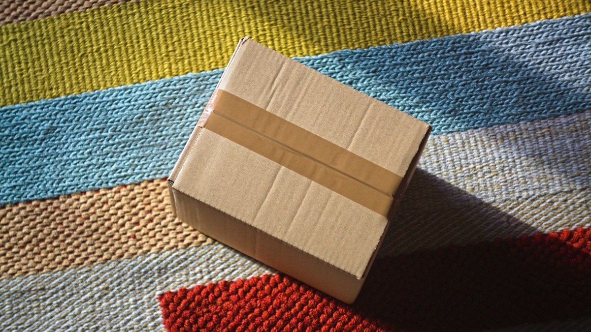 Sealed cardboard return package sitting on a striped rug