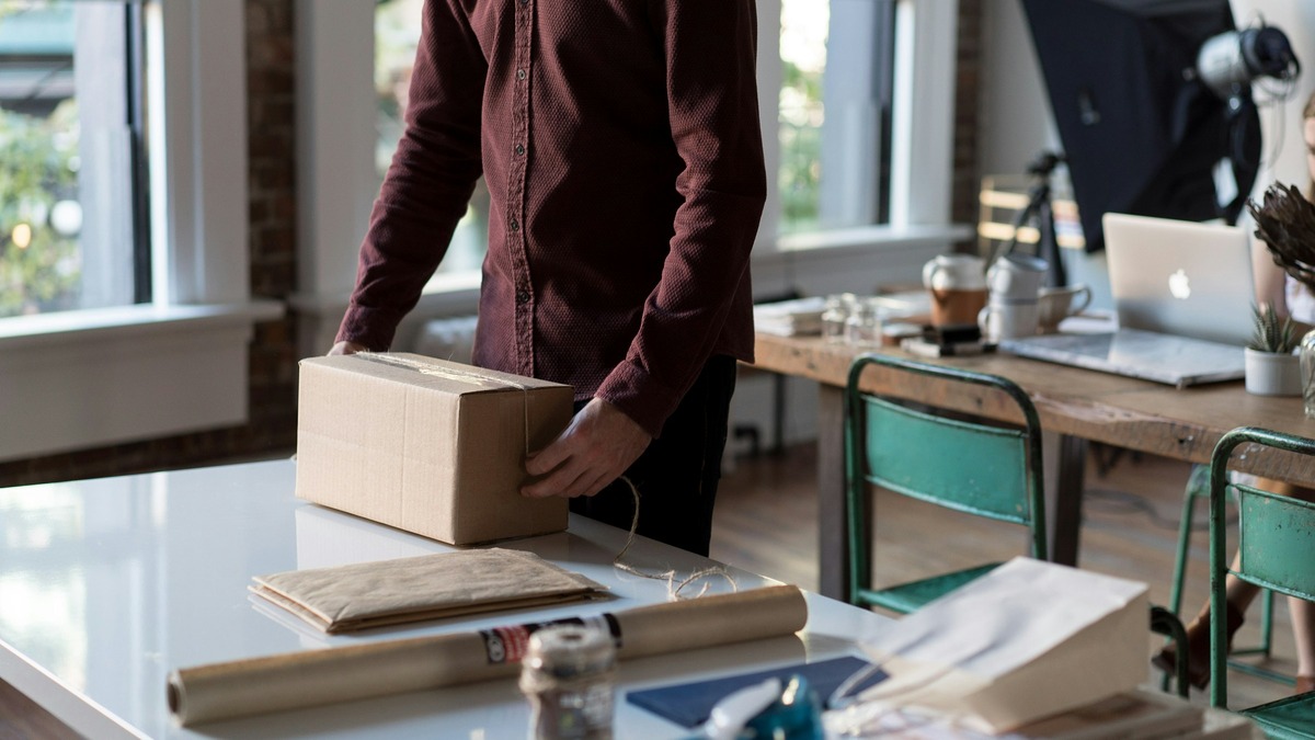Person packing a cardboard box for shipment at a work table