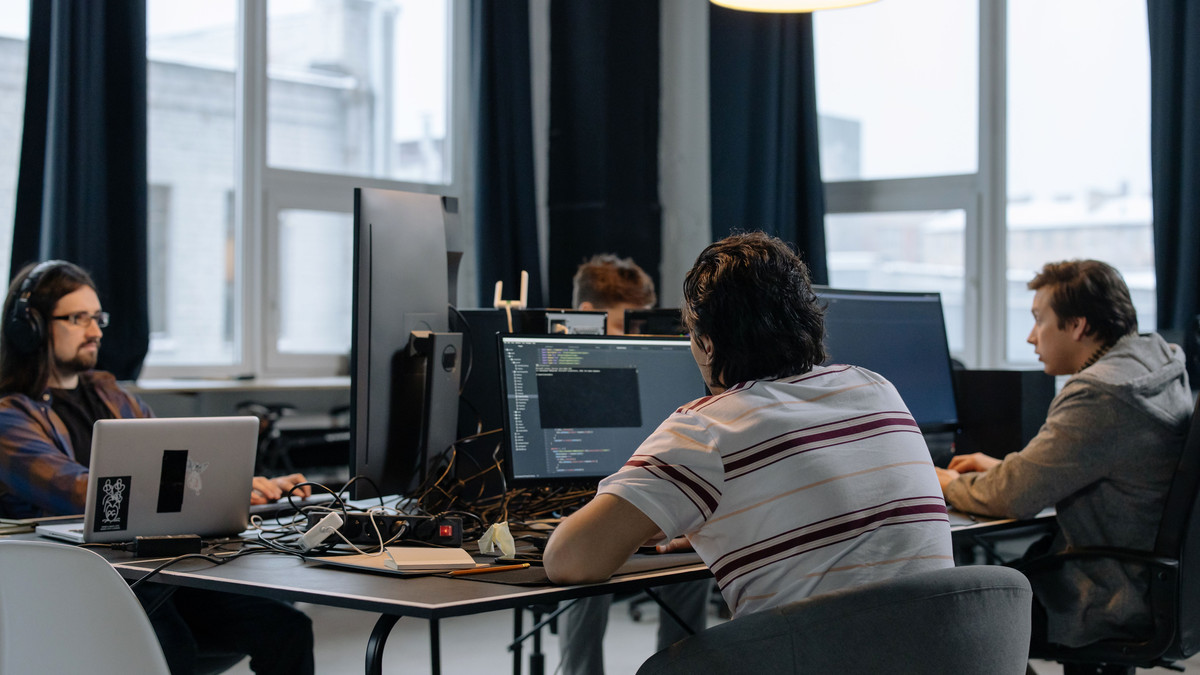 Small team of developers working at desks and monitors in a bright office